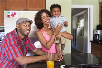 Portrait of smiling mixed race couple and baby son in kitchen