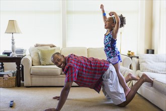 Mixed race father and daughter playing on floor in livingroom