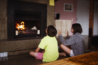 Mixed race children relaxing by fireplace in living room