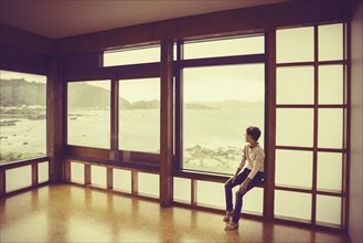 Mixed race boy looking out window