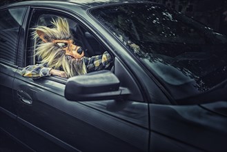 Mixed race boy wearing wolf mask and driving car