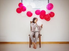 Mixed race girl blowing up balloons for party