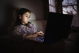Mixed race girl using laptop at night