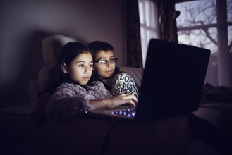 Mixed race sisters using laptop at night