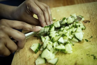 Close up of mixed race woman chopping cucumber in kitchen