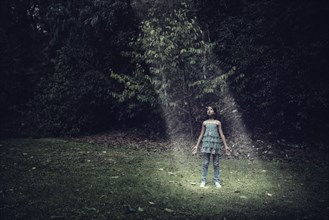 Mixed race girl standing in beam of light outdoors