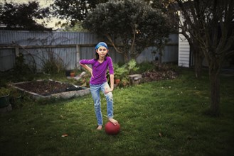 Mixed race girl playing with soccer ball in backyard