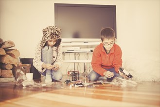 Mixed race brother and sister playing on living room floor