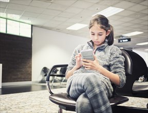 Mixed race girl using cell phone in airport