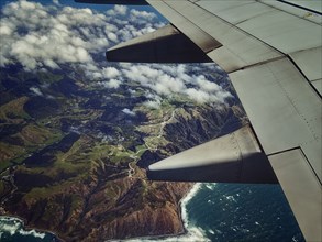 Aerial view of airplane wing flying over coastline