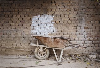 Empty wheelbarrow near brick wall