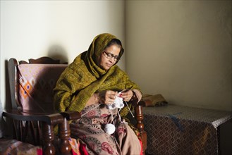 Older woman knitting baby clothes