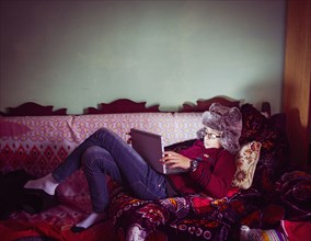 Mixed race boy wearing fur hat using digital tablet on sofa