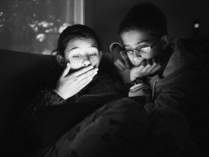 Mixed race children using digital tablet at night