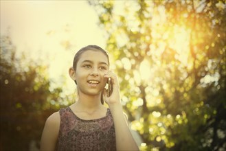 Mixed race girl talking on cell phone outdoors