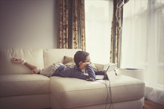 Mixed race boy using digital tablet on sofa