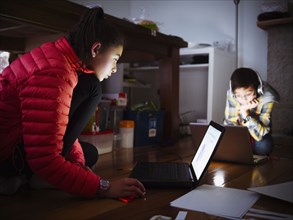 Mixed race children using laptops on floor