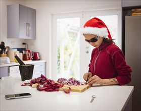 Mixed race girl cooking in Santa hat