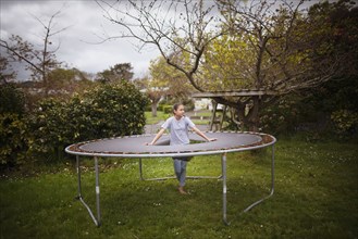 Mixed race girl standing in broken trampoline