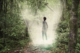 Mixed race boy standing in forest portal