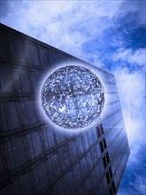Low angle view of orb floating near highrise building