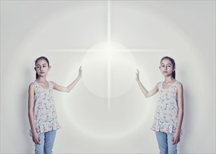 Mirror image of mixed race girl reaching for light