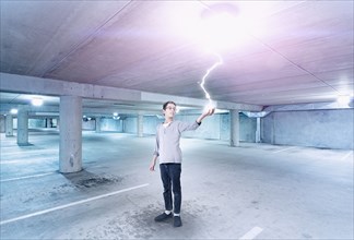 Mixed race boy holding lightning in parking lot