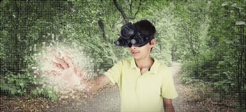 Mixed race boy wearing virtual reality goggles in remote forest