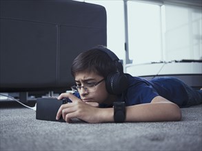Mixed race boy using cell phone on floor