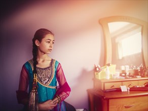 Mixed race girl wearing Indian dress in bedroom