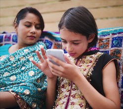 Mother and daughter in Indian clothing using cell phone