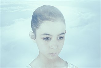 Face of wide-eyed Mixed Race girl in clouds