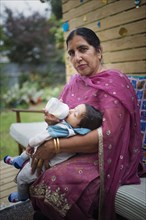 Indian grandmother feeding bottle to grandson