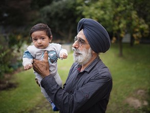 Indian grandfather holding baby grandson