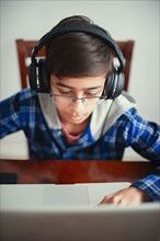 Mixed Race boy listening to laptop with headphones