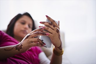 Woman with henna tattoos on hands texting on cell phone