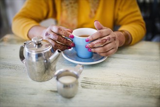 Woman with henna tattoo on hands drinking tea