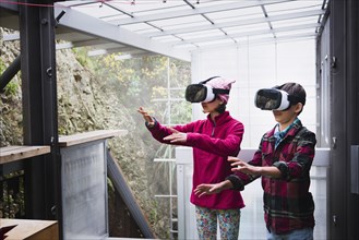 Mixed Race brother and sister using virtual reality goggles on veranda