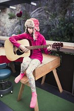 Mixed Race girl playing acoustic guitar on veranda