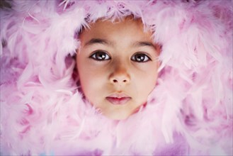 Face of Mixed Race girl surrounded by pink feather boa