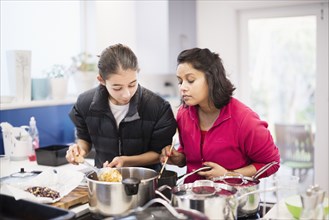 Mother and daughter looking down at cooking food
