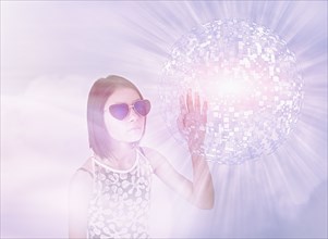 Mixed Race girl wearing sunglasses touching hovering pixel sphere