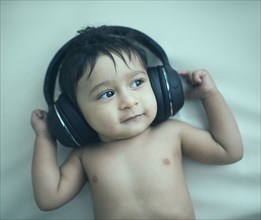 Indian baby boy listening to headphones