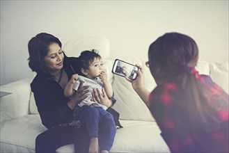 Indian woman photographing mother and son with cell phone