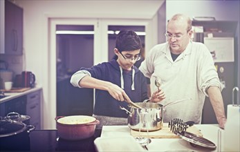 Father watching son cooking in kitchen
