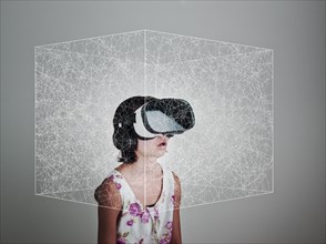 Mixed Race girl wearing virtual reality goggles in floating box