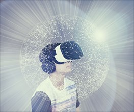Mixed Race boy wearing virtual reality goggles in glowing sphere