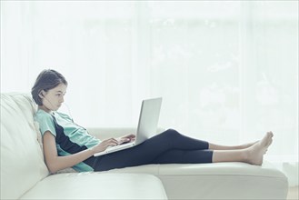 Mixed Race girl on sofa using laptop