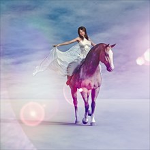 Woman wearing white dress riding horse