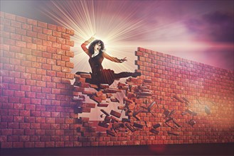 Fierce woman kicking through brick wall